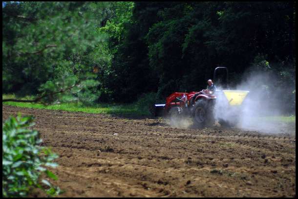 We broke the new ground with a Woods Disk Harrow and then we spread lime and fertilizer on top of the roughly tilled soil.